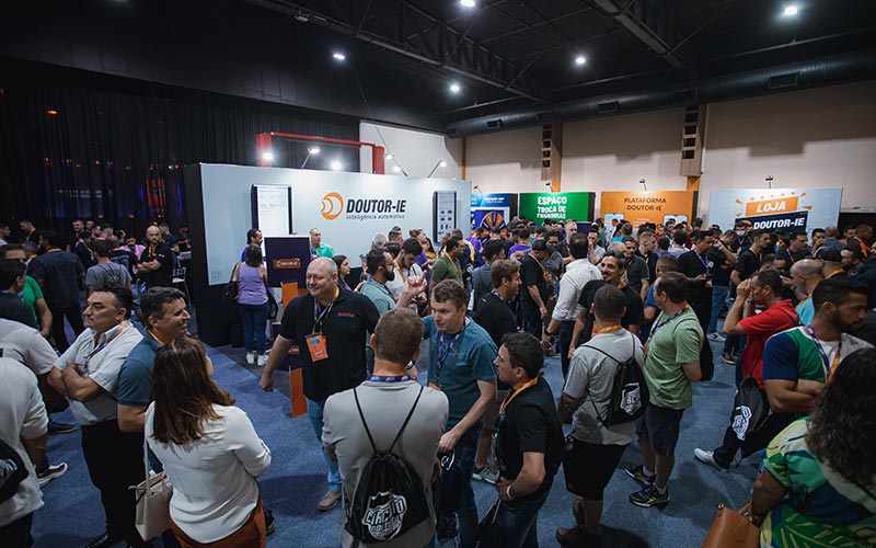 Participantes, palestrantes e expositores no salão da feira de negócios próximos ao stand da Doutor-IE.