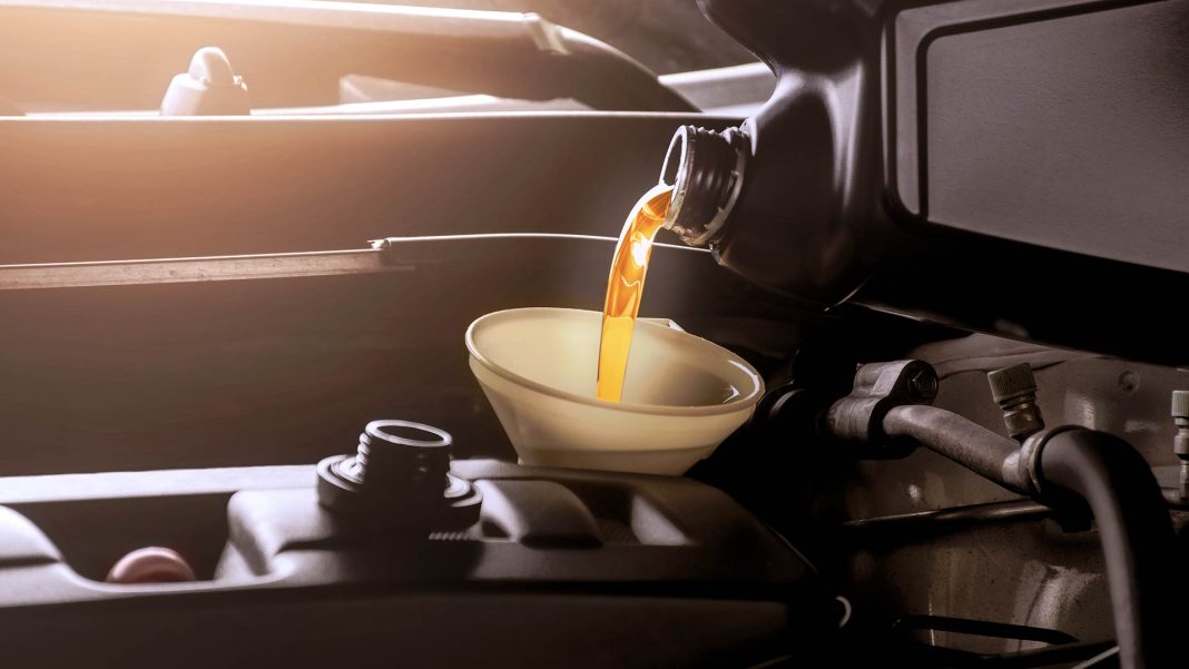 Blog Doutor-ie Mecânico reabastece fluído lubrificante do motor de um veículo.